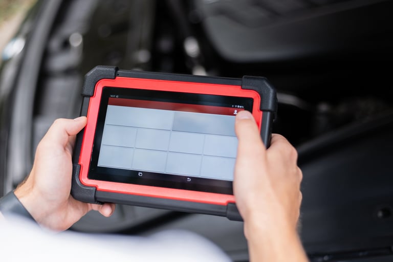 Mechanic using a digital diagnostic scanner to check car systems inside the vehicle